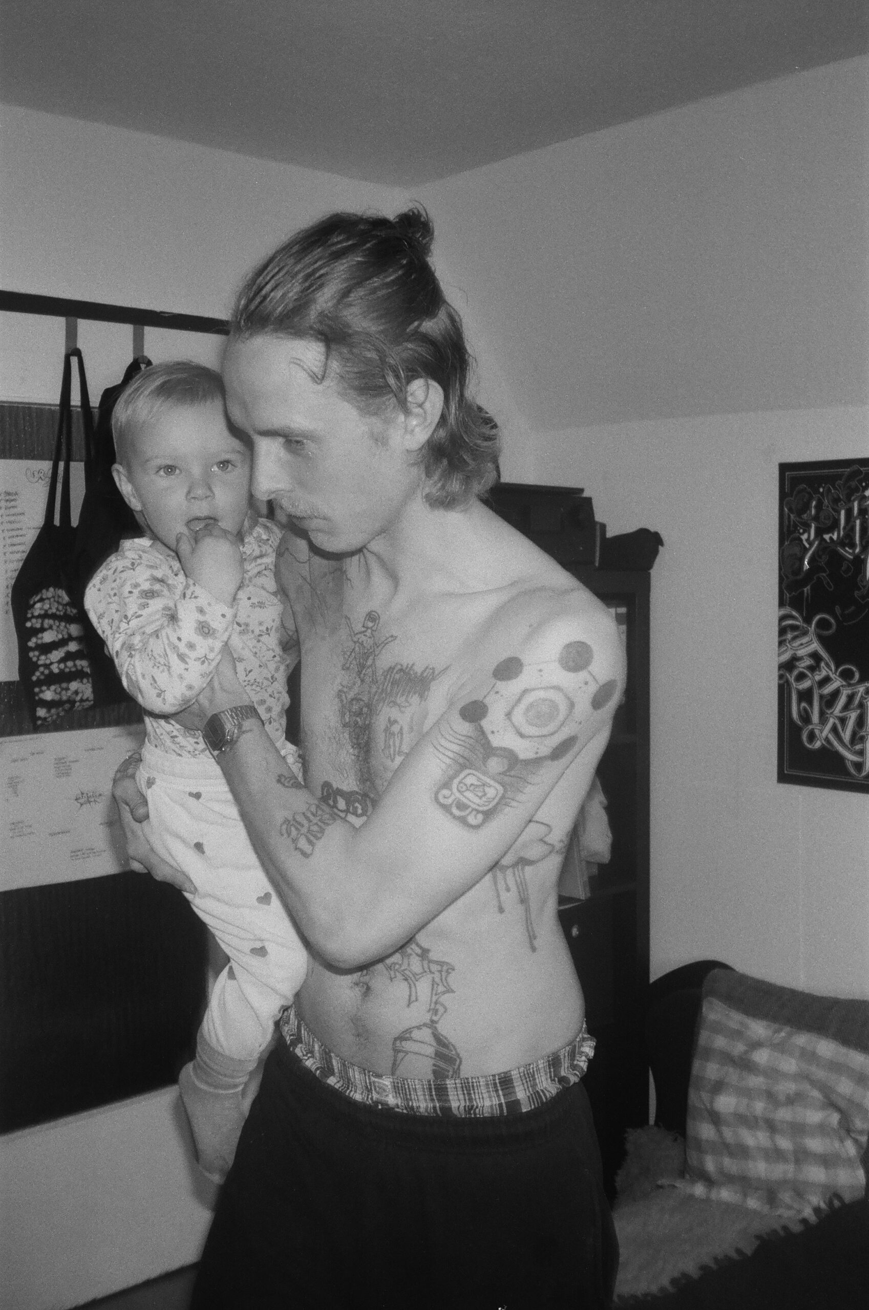 Vater hält sein Kind, schwarz-weiße analoge Aufnahme, die Verbundenheit und Alltagsmomente zwischen Eltern und Kind zeigt.